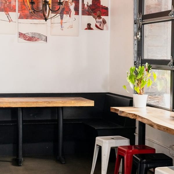 Baka Umai's dining area with a wooden table, black booth seating, and basketball-themed art.