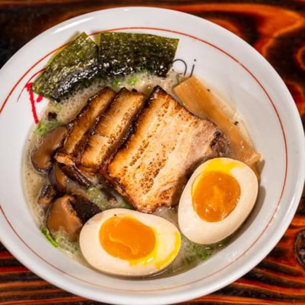 Ramen bowl with pork belly, soft-boiled eggs, mushrooms, bamboo shoots, and seaweed.