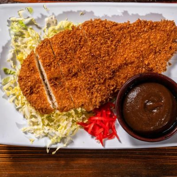 Crispy tonkatsu, sliced and served with shredded cabbage, pickled ginger, and a side of curry sauce.